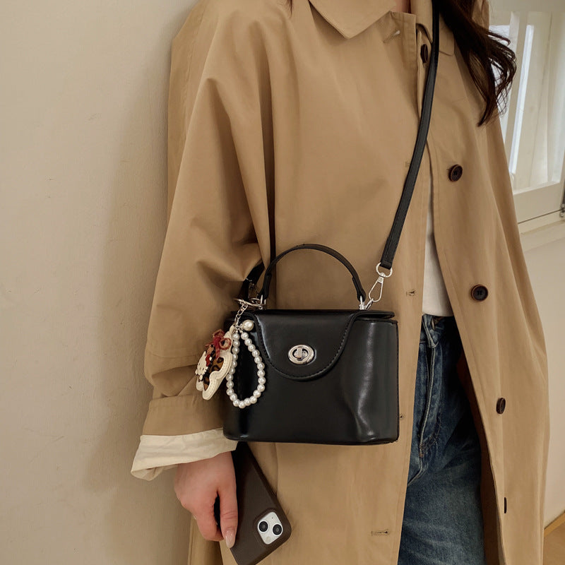 Damen Mini-Handtasche im elegant geschwungenen Design mit spielerischem Anhänger