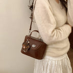 Damen Mini-Handtasche im elegant geschwungenen Design mit spielerischem Anhänger